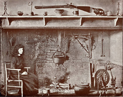 A woman sitting at a fireplace containing a fireback